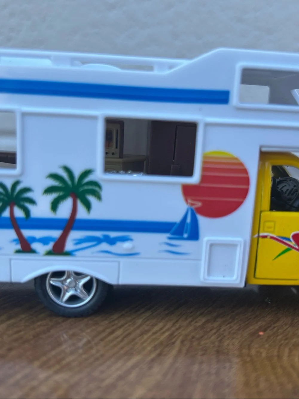 Bright yellow and white toy camper van with colorful beach graphics collectible